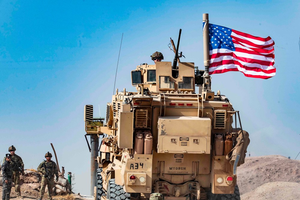Image: A U.S. soldier sits atop an armoured vehicle during a demonstration by Syrian Kurds against Turkish threats at a US-led international coalition base on the outskirts of Ras al-Ain town in Syria's Hasakeh province near the Turkish border