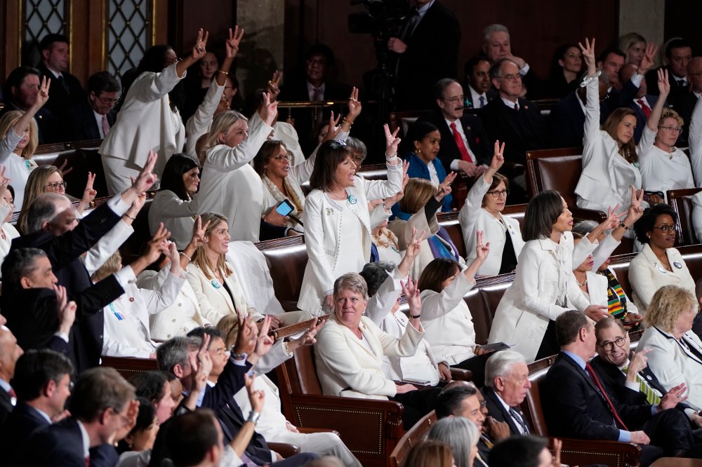 Democratic members of Congress wearing white, hold up three fingers for the HR3 health care bill
