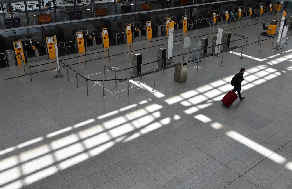 Image: A passenger walks in an empty terminal at the "Franz-Josef-Strauss" airport in Munich