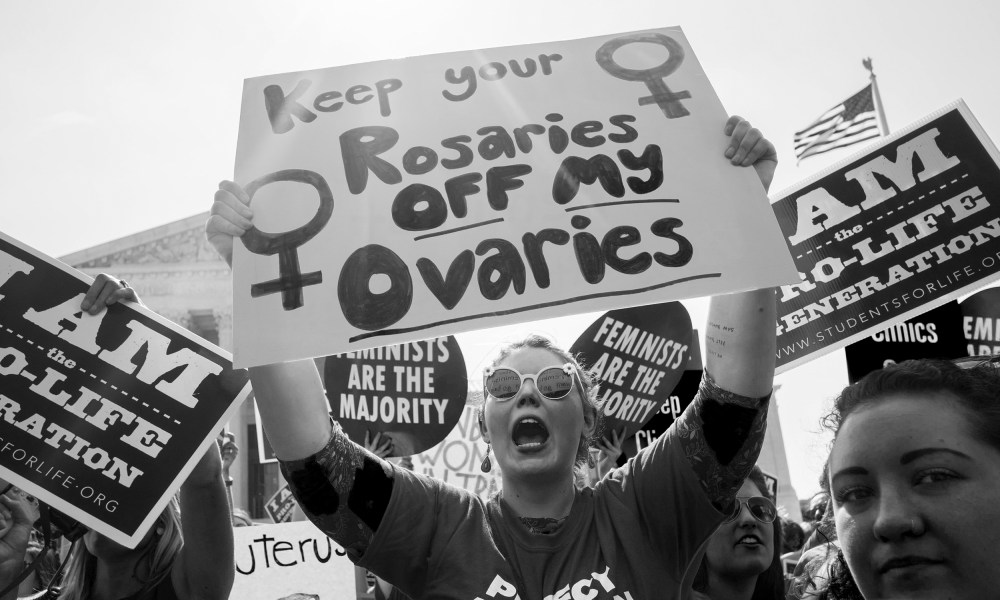 Image: Pro-choice activist holds sign that reads,"Keep your rosaries off my ovaries".