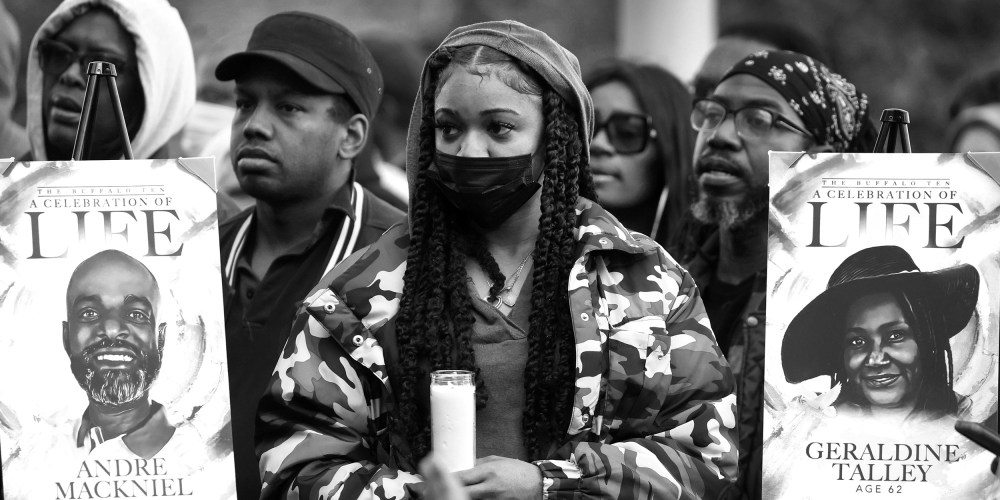 Image: People hold candles and two posters that show portraits and have text that read,"A celebration of life".