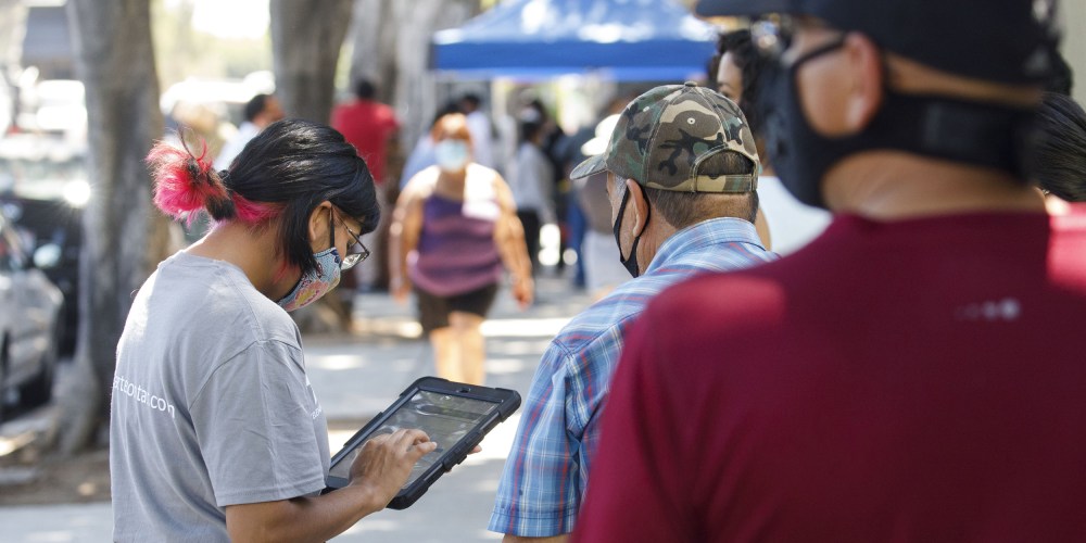 Image: A youth ambassador conducting a census interview with people walking by.