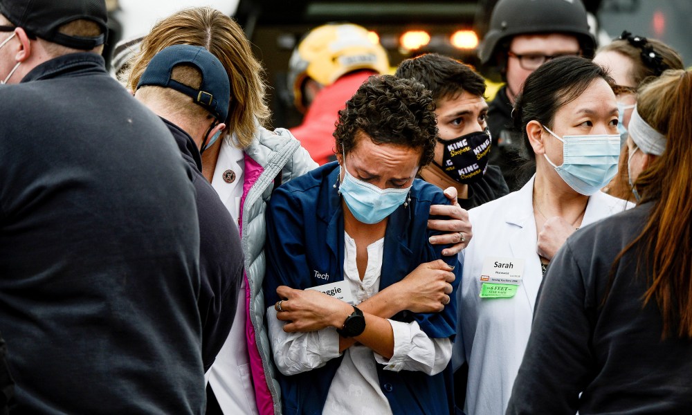 Image: A woman consoles a King Soopers pharmacy technician after a shooting at the grocery store in Boulder