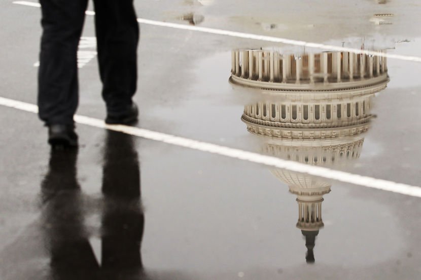 The dome of the U.S. Capitol Building is reflected in a puddle on a rainy morning in Washington