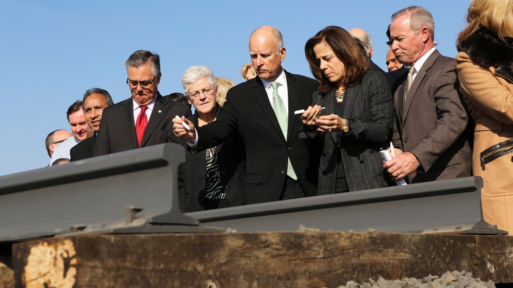 California Governor Jerry Brown (C) and his wife, Anne Gust, prepare to sign a railroad rail during a ceremony for the California High Speed Rail in Fresno, Calif., on Jan. 6, 2015. (Photo by Robert Galbraith/Reuters)