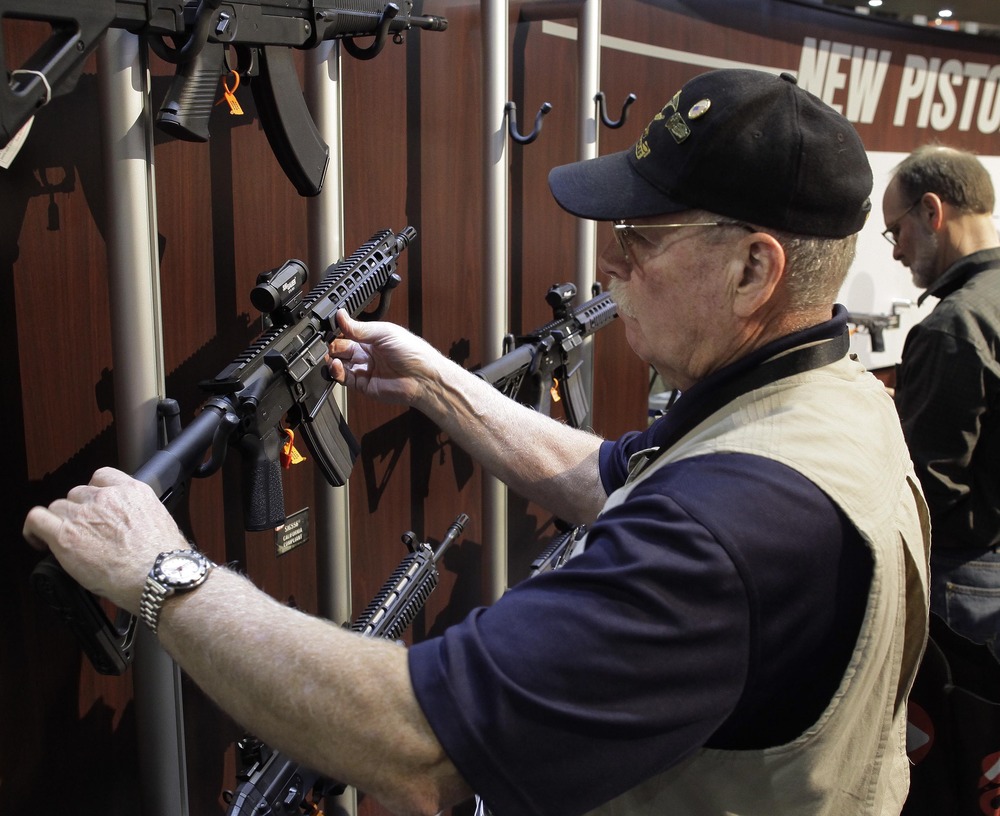 An industry retailer examines various SIG SAUER sport rifles at the National Shooting Sports Foundation's Shooting, Hunting and Outdoor Trade show, Tuesday, Jan. 18, 2011 in Las Vegas. (AP/Julie Jacobson)