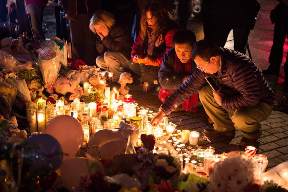 Zong Yang Tan, right, and Guan Fu Jiang light candles at the makeshift memorial in the center of Sandy Hook village on Monday in Newtown, Conn. (David Friedman / NBC News)