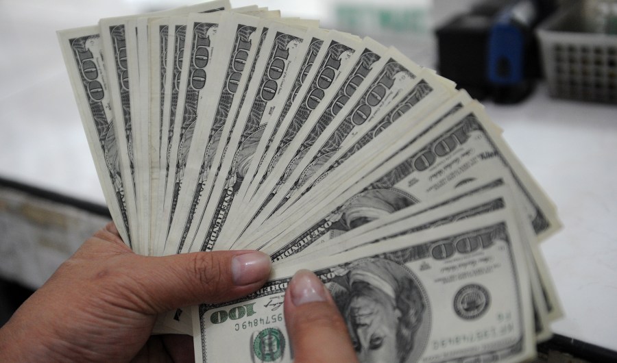 An employee at a money changer counts $100 bills.