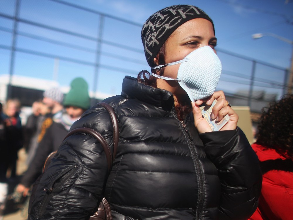 Rockaway resident Saajida O'Quinn wears a protective mask as she prepares to vote in a makeshift tent set up as a polling place at Scholars' Academy, PS 180, in the Rockaway neighborhood on November 6, 2012 in the Queens borough of New York City. The...
