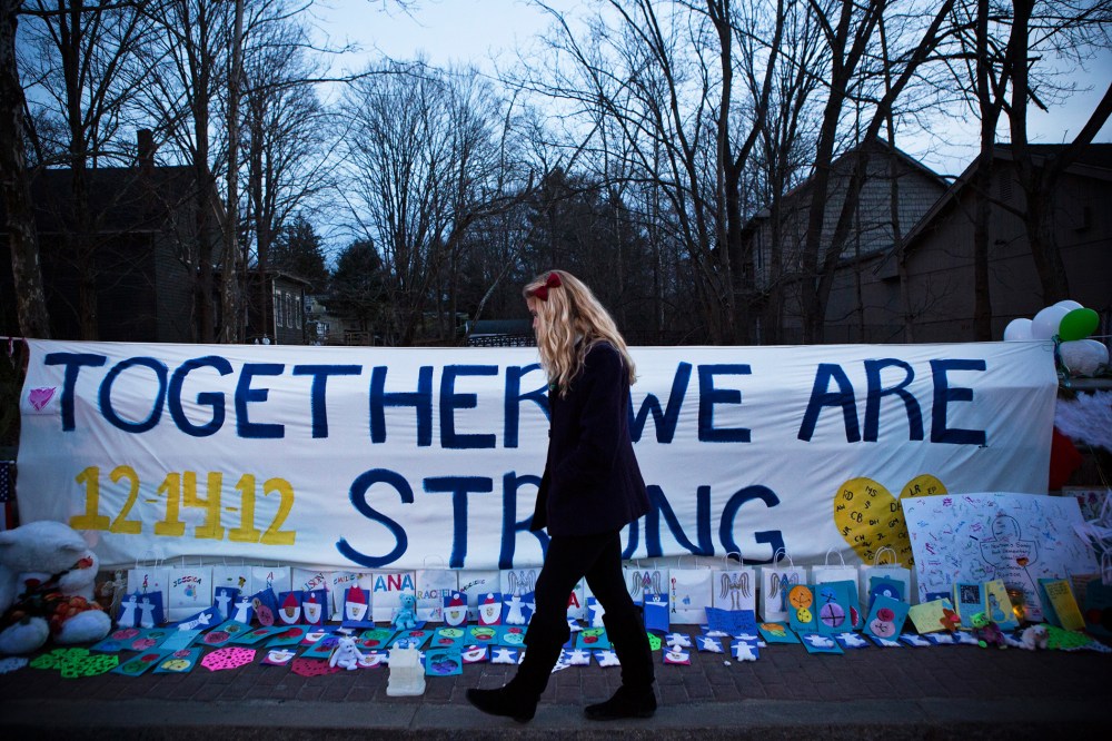 A woman walks past a sign that reads "Together we are Strong" at a memorial for those killed in the school shooting at Sandy Hook Elementary School on Dec. 24, 2012 in Newtown, Conn. (Photo by Andrew Burton/Getty)