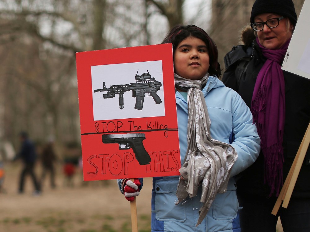 Luna Miller holds a anti gun sign while participating in a rally and march across the Brooklyn Bridge with One Million Moms for Gun Control, a gun control group formed in the wake of last month's massacre at a Newtown, Connecticut elementary school on...