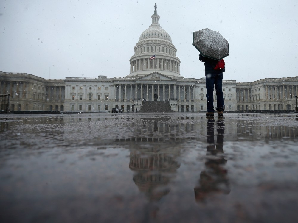 A tourist takes cover underneath an umbrella while snapping a photo of the U.S. Capitol as snow and rain falls March 6, 2013 in Washington, DC. A late winter storm is expected to cover the Mid-Atlantic region after dropping almost a foot of snow across...