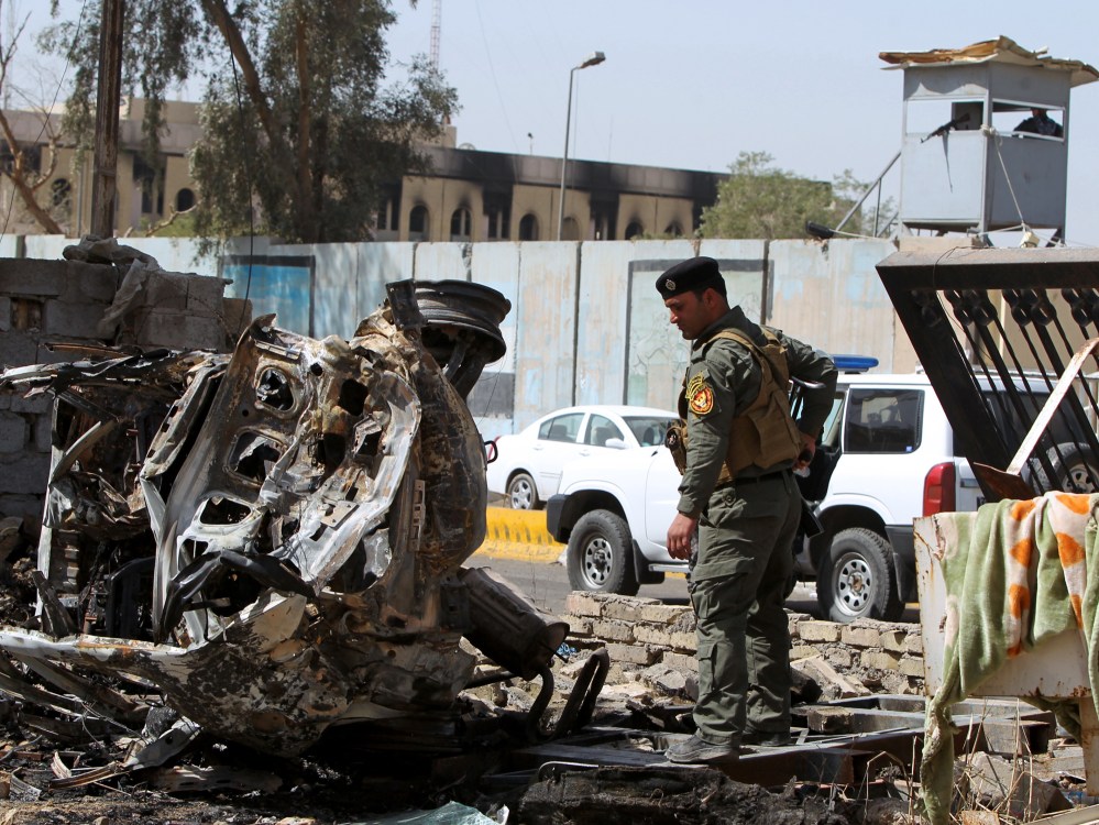 A member of Iraq's internal security forces inspects the damage outside the Iraqi justice ministry in Baghdad on March 15, 2013, a day after militants staged an apparently unsuccessful assault. A coordinated string of bombings and a brazen assault on...