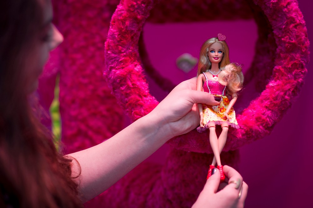 A woman holds a Barbie doll at 'Barbie: The Dreamhouse Experience'  in Berli, April 12, 2013.