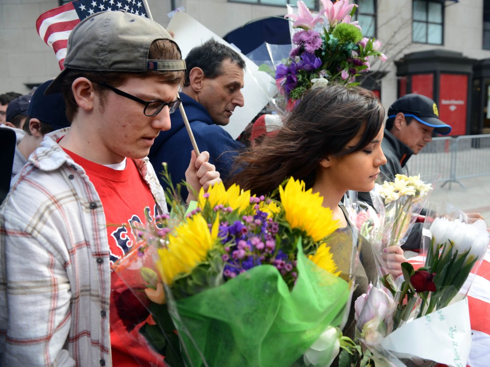 After the barricades were moved up along Boylston street to the corner with Berkeley people walk along holding flags and memorials following yesterday's bomb attack on the Boston Marathon April 16, 2013 in Boston, Massachusetts. Security is tight in...