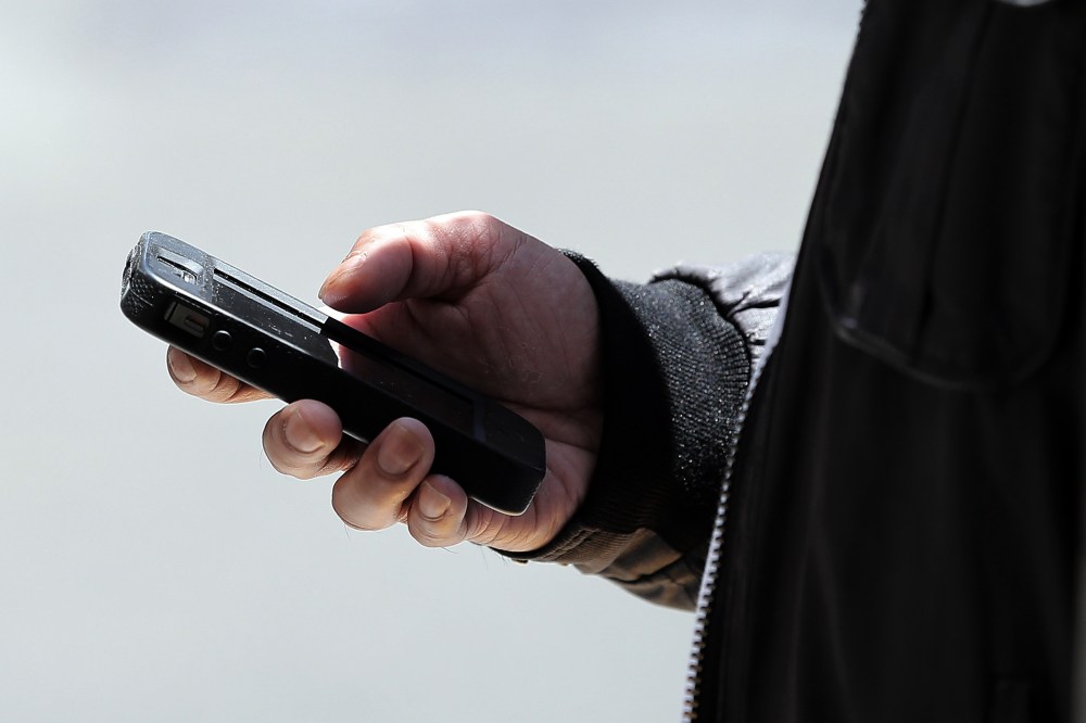 A pedestrian uses a smartphone as he walks along Market Street on June 5, 2013 in San Francisco, California.