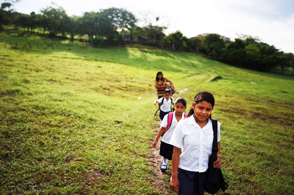 Girls walk to school accompanied by their mother, in the village of Metalio, El Salvador, July 1, 2013.