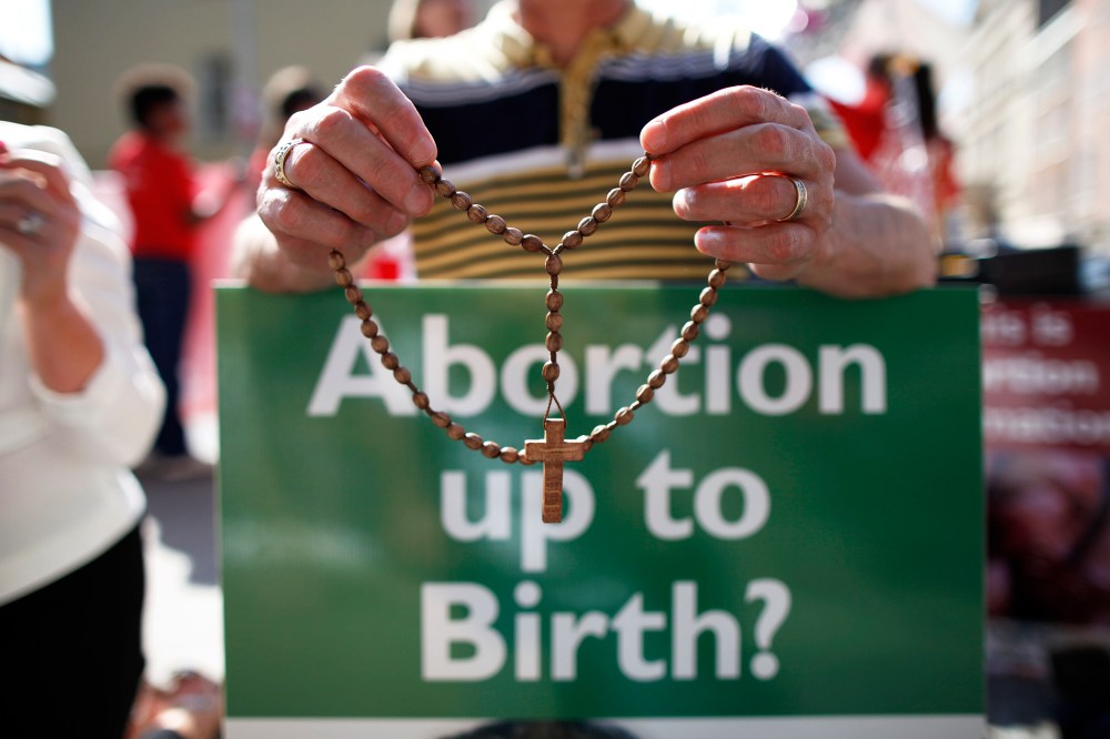 A protester holds rosary beads with a anti-abortion placard. (Photo by Peter Muhly/AFP/Getty)