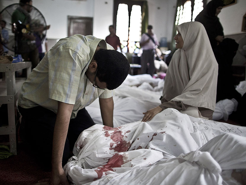 Egyptians mourn over a body wrapped in shrouds at a mosque in Cairo on August 15, 2013, following a crackdown on the protest camps of supporters of ousted Islamist president Mohamed Morsi the previous day.  (Photo by Mahmoud Khaled/AFP/Getty Images)