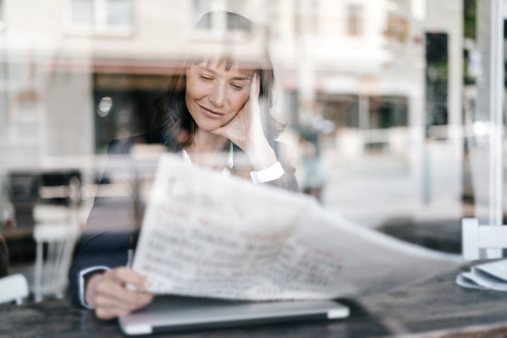 Businesswoman sitting cafe, reading newspaper