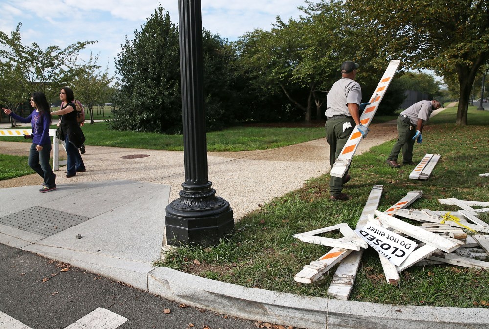 Tourists walk past as U.S. Park Service workers remove barricades on October 17, 2013 in Washington, DC.