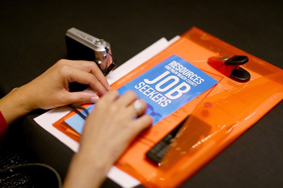 A job seeker holds employment papers as she attends career fair in West Palm Beach, Nov. 7, 2013.