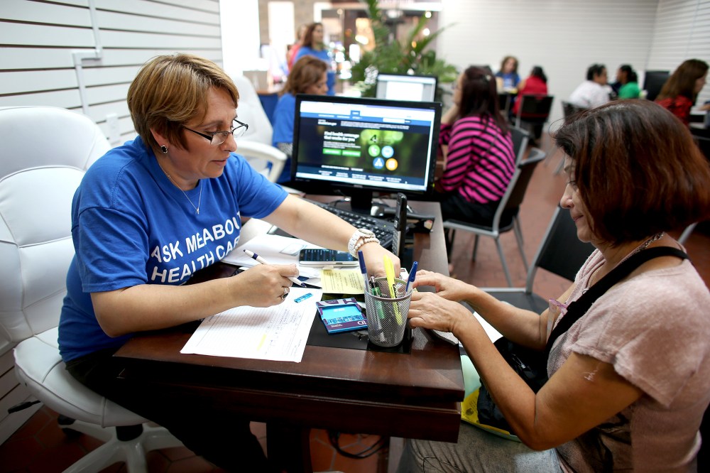 Mercy Cabrera (L), an insurance agent with Sunshine Life and Health Advisors, helps Amparo Gonzalez  purchase an insurance policy under the Affordable Care Act at the store setup in the Westland Mall on Nov. 14, 2013 in Hialeah, Fla.