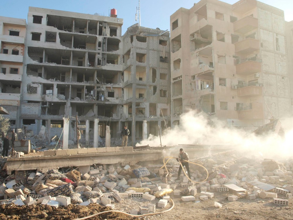 Residents stand near buildings damaged by what activists said were missiles fired by a Syrian Air Force fighter jet loyal to President Bashar al-Assad in Daraya January 17, 2013, in this picture provided by Shaam News Network . (Photo by Kenan Al...