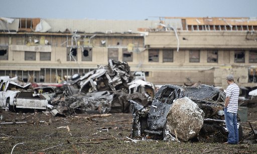A man looks at a boulder that hit a car after a tornado struck Moore, Oklahoma, May 20, 2013. A 2-mile-wide (3-km-wide) tornado tore through the Oklahoma City suburb of Moore on Monday, killing at least 51 people while destroying entire tracts of homes...