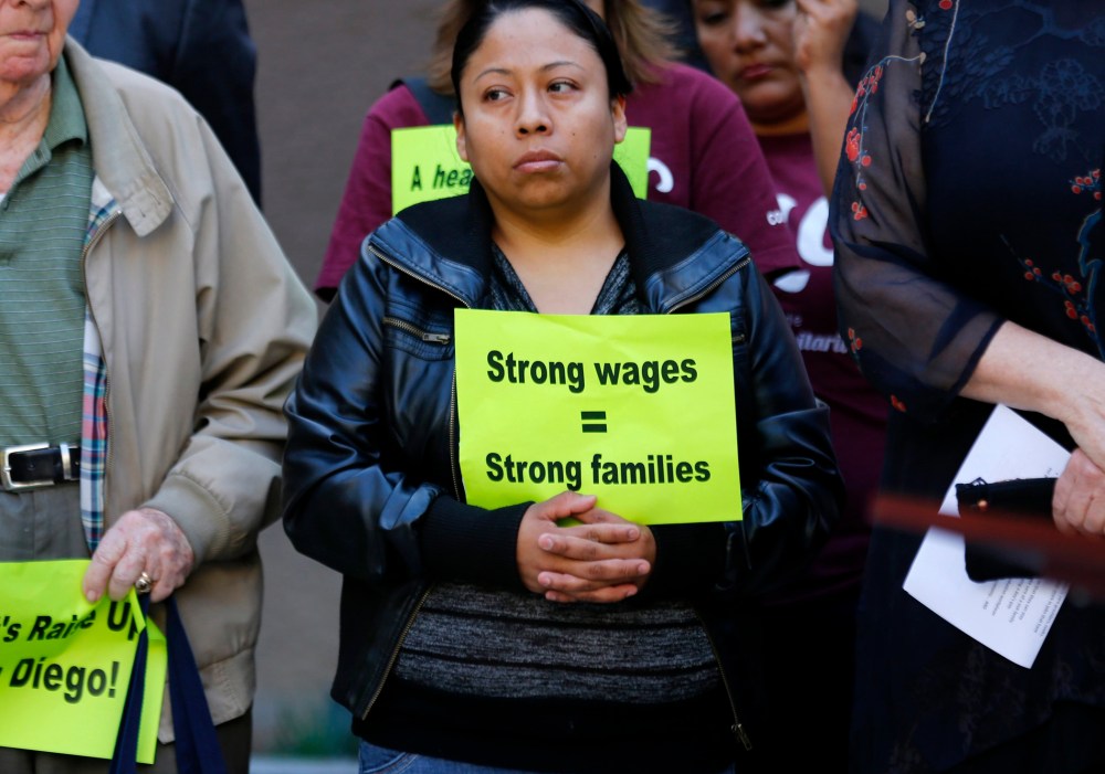 A supporter holds a sign promoting a movement to raise the minimum wage in San Diego, California, March 12, 2014.