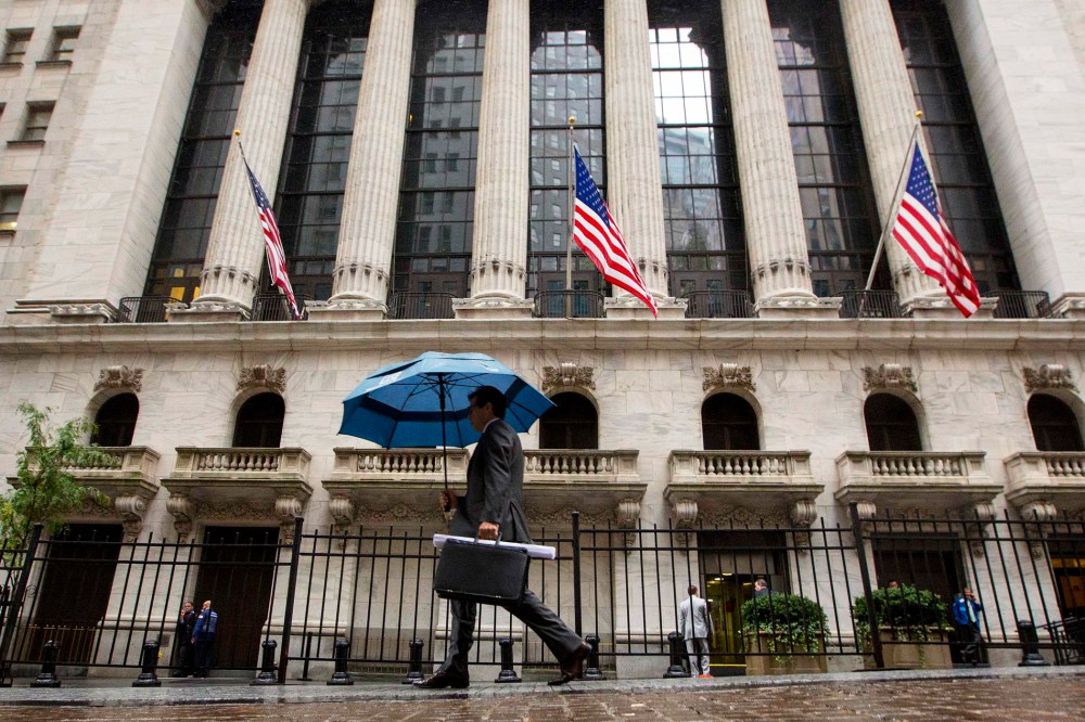 A man carries an umbrella in the rain as he passes the New York Stock Exchange on Oct. 16, 2014.