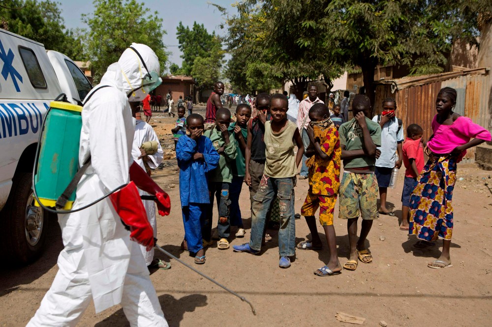 Children watch as a health worker sprays disinfectants outside a mosque in Bamako, Mali on Nov. 14, 2014.