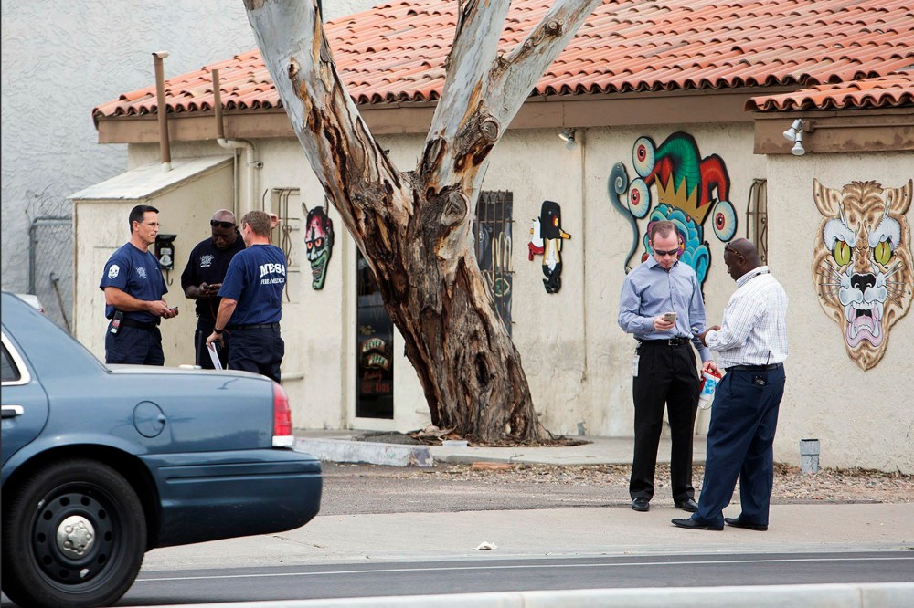 Police confer near a tattoo parlor at one of the scenes of a multiple location shooting that has injured at least four people in Mesa, Arizona on March 18, 2015.