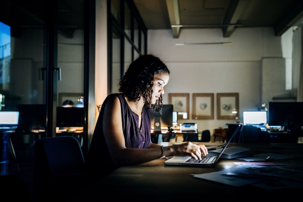 Casual young businesswoman working late on a laptop