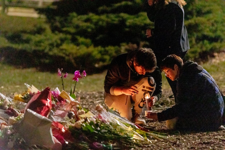 People light a candle at The Rock during a vigil on Feb. 14, 2023, at Michigan State University in East Lansing.