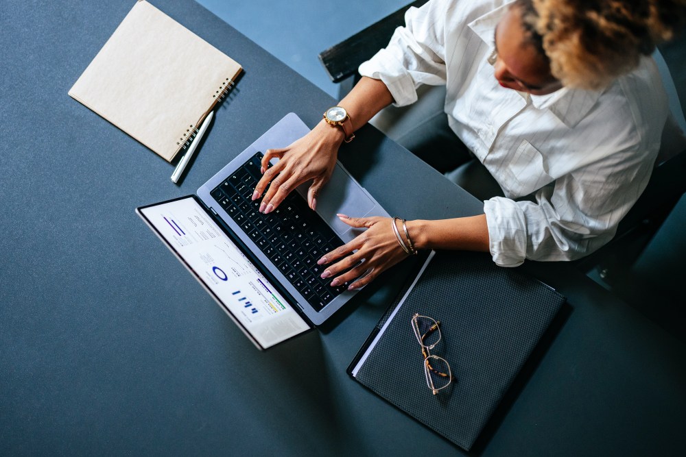 High Angle View Of Unrecognizable Woman Typing Business Report On A Laptop Keyboard In The Cafe