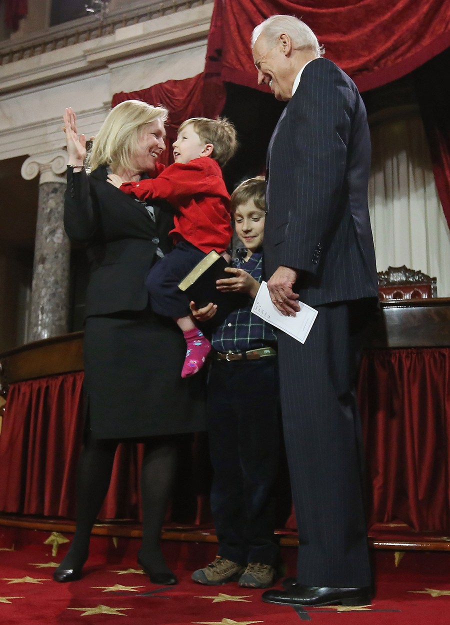Gillibrand holds up her hand as she carries her son 