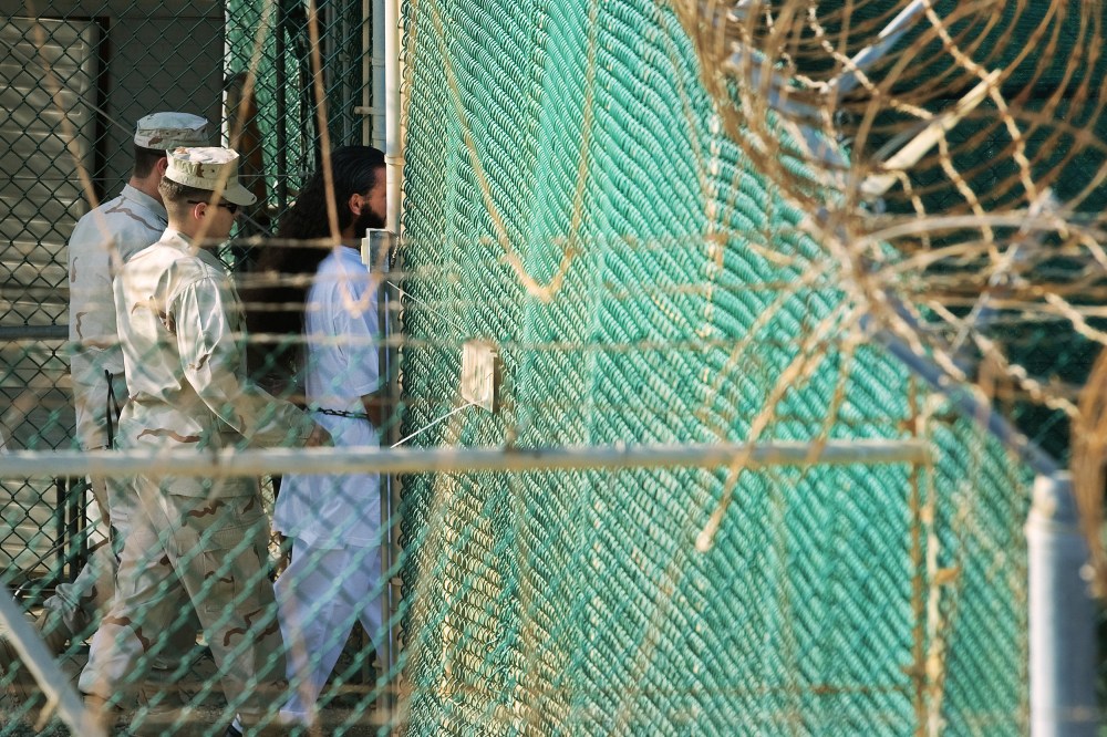Guards walk behind a detainee