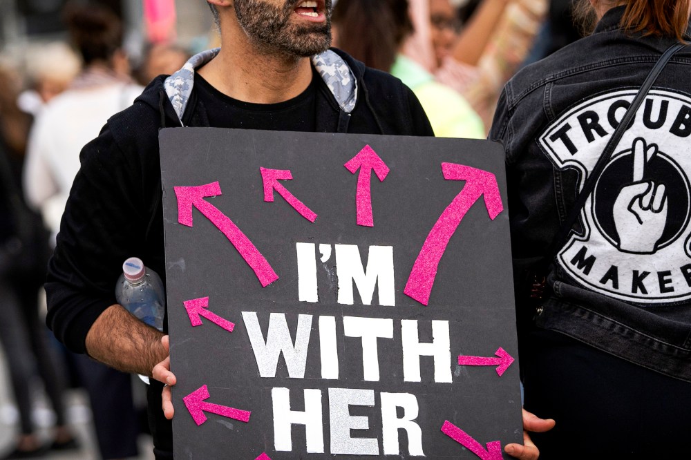 An activist holds a placard that says I'm with her.