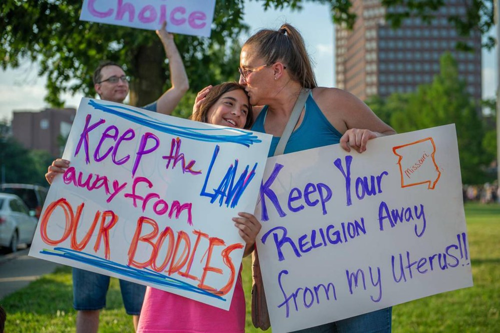 Eleven-year-old Giuliana Cangelosi, left, and her mother Nichole Cangelosi share a moment together while attending a protest opposing the Supreme Court's ruling overturning federal protections for abortion rights June 24, 2022, in Mill Creek Park at Country Club Plaza in Kansas City, Missouri.