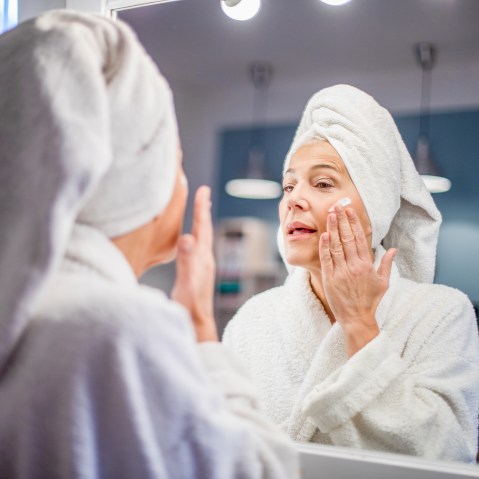 Mature woman applying face cream.