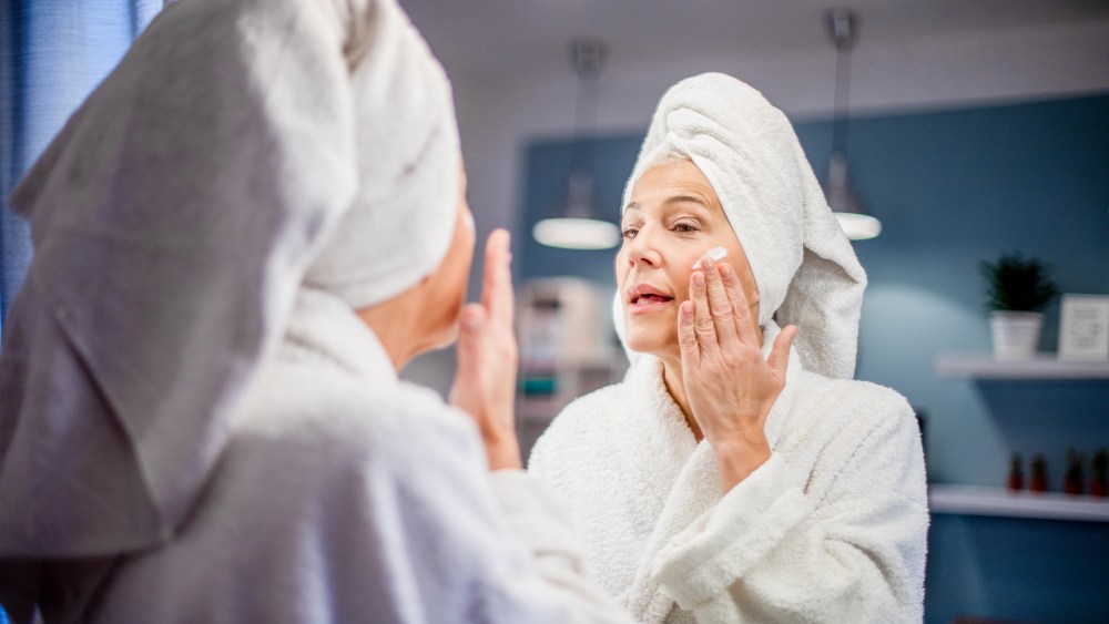 Mature woman applying face cream.