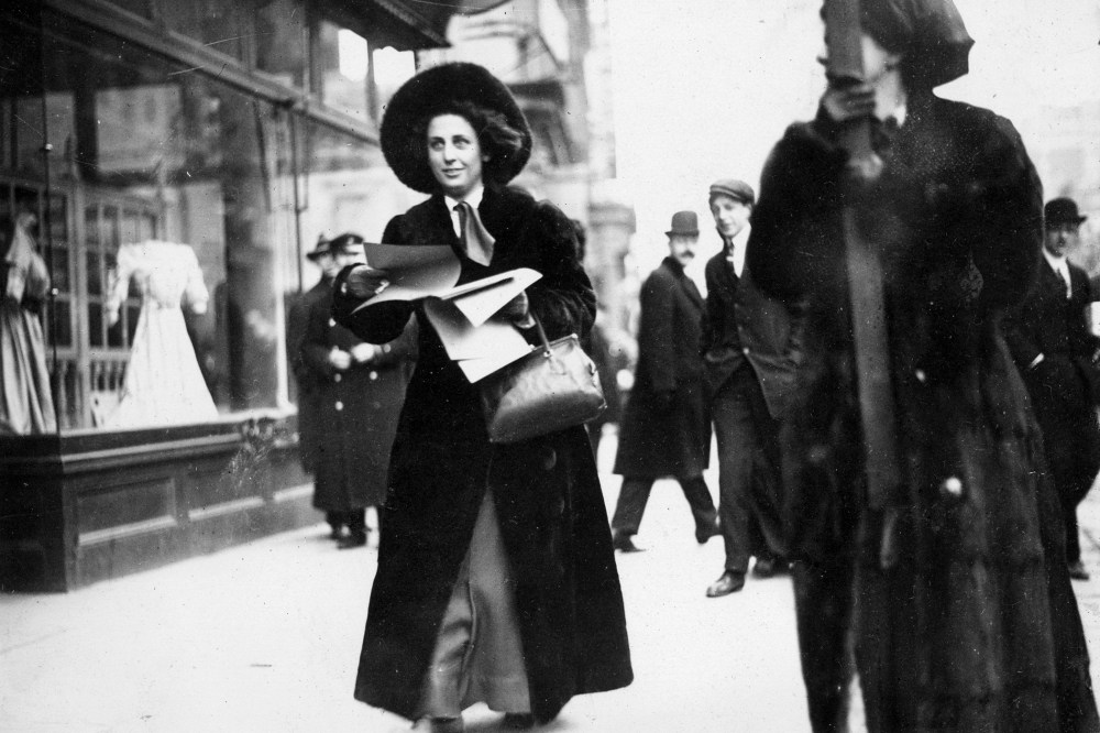 Miss Martha Gruening distributes literature publicizing the Women's Suffrage Movement to passers-by outside the Lyceum Theatre, circa 1912.