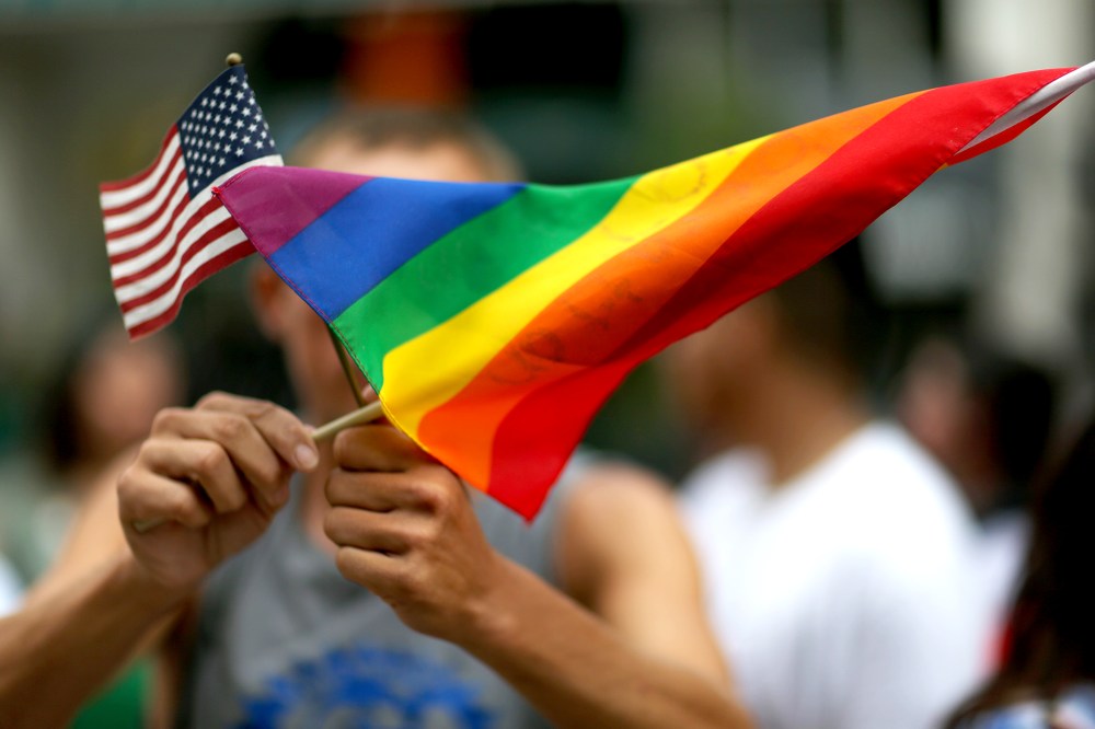 A protester holds an American flag and rainbow flag.