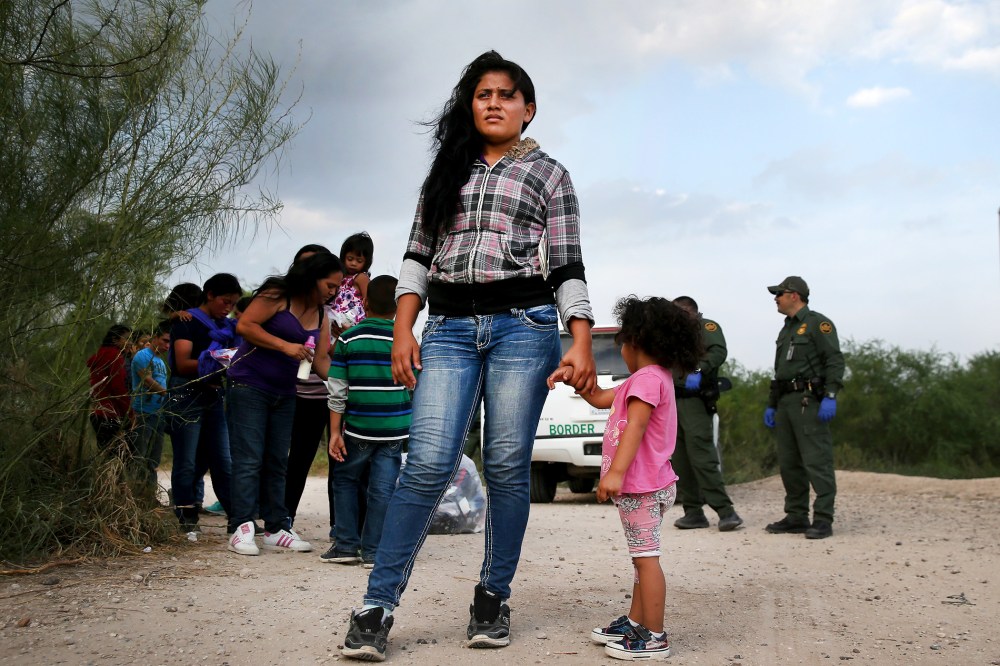 Honduran immigrants wait as a Border Patrol vehicle arrives to transport their group to a processing center, July 24, 2014 in Mission, Texas.