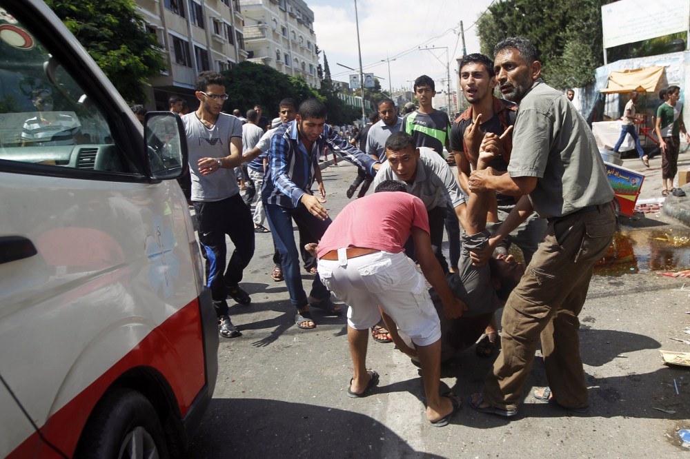 Palestinians carry an injured man following an Israeli military strike on a UN school in Rafah, in the southern Gaza Strip on Aug. 3, 2014.