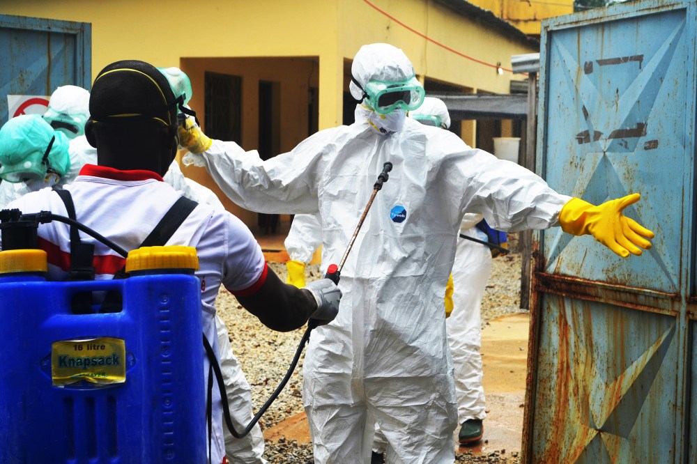Guinea's Red Cross health workers wear protective suits prepare to carry the body of a victim of Ebola near the hospital Donka in Conakry, Sept. 14, 2014.