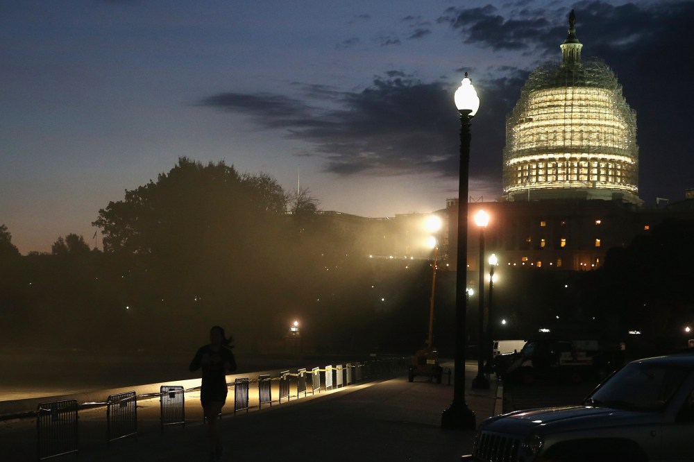 The sun begins to rise behind the dome of the US Capitol that is covered in scafollding for repairs, on Nov. 4, 2014 in Washington, DC.
