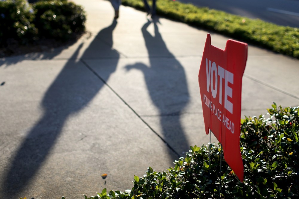 Voters cast shadows as they walk to the polling station past a sign pointing the way to The Coliseum where a polling station is setup on Nov. 4, 2014 in St Petersburg, Fla.