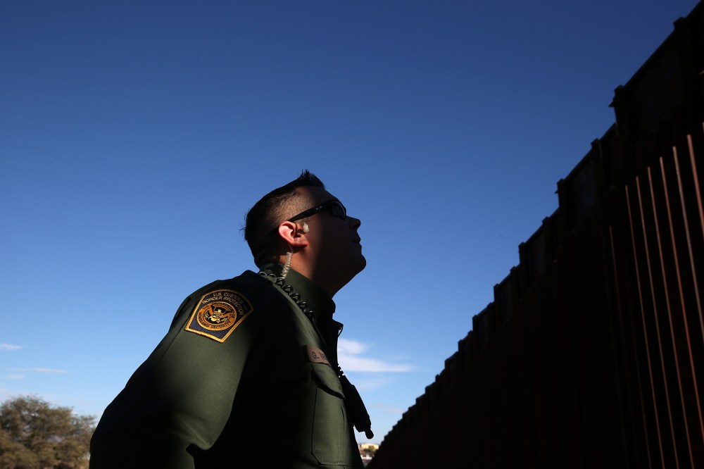 A U.S. Border Patrol agent stands next to the U.S.-Mexico border fence on Dec. 9, 2014 in Nogales, Ariz.